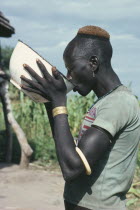 Dinka man drinking groundnut gruel at ceremony welcoming young men back to village after spending eight weeks at fattening camp.