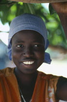 Portrait of smiling Dinka girl wearing striped headscarf.