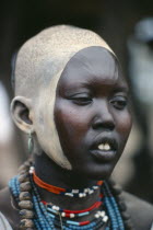 Portrait of young Dinka woman with facial decoration of ash paint and scarification.