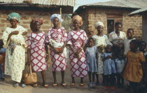 Polygamy.  Wives of the same man  framed in window behind  wearing dresses made of the same material.