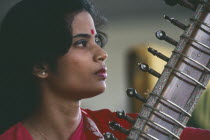 Female Indian musician playing the sitar.  Cropped view showing neck of instrument only.