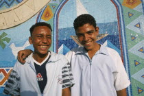 Two smiling boys  one with arm resting across shoulders of other.