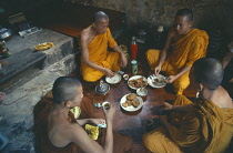 Buddhist monks eating meal in monastery.