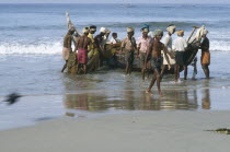 Fisherman dragging boat from the sea on to beach.Kerela Kovalum