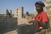 Mshikimano squatter settlement. Isabella Humbidi at site of new low cost house she and her husband are building after being taught how to make bricks and tiles.