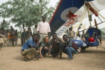 Travel writer and explorer Christina Dodwell with microlight aircraft and group of local men and children.