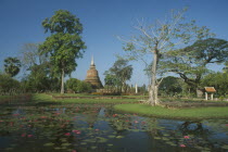 View over lotus flowers on stream with chedi in background at Sukhothai Historical Park.