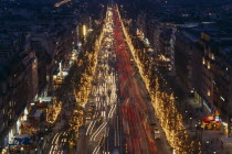Les Champs Elysees at night with illuminated shop fronts and traffic light trails.
