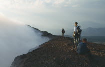 People standing on the rim of the smoking crater.