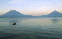 View of a boat sailing on the lake with two Volcanoe peaks in the distance.