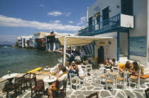 People at waterside cafe with gallery above.