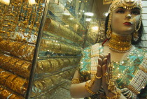 The Gold Souk.  Shop window display with mannequin draped in gold jewellery beside large display of gold bracelets.