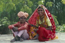 Woman and young boy sitting together wearing traditional clothing.