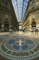Galleria Vittorio Emanuele II shopping arcade interior with arched glass roof and mosaic floor lined with designer shops.