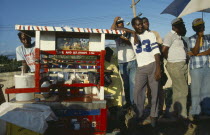 Men standing at drinks vendor stall.