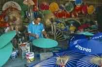 Bo Sang Umbrella Making Centre. Man painting umbrella amongst colourful display of umbrellers.Center Colorful