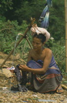 Hmong Tribeswomen washing clothes from wooden water pipe.