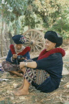 Yao Tribeswomen sitting on ground sewing clothes.