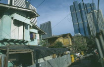 Inner city slum district adjacent to silom road. View from alleyway towards slum housing with corporate highrise buildings behind.