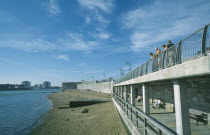 Old Portsmouth. Occupied strectch of beach next to the Walls with people looking over railings towards the Square Tower.