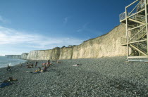 Occupied stretch of pebble beach at the cliff base with the stair construction on the right.