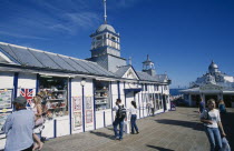 England, East Sussex, Eastbourne, Pier gift shops with visitors walking past.