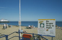Child safety awarness sign Kid Zone displayed next to railings on busy beach.