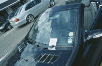 Black Mercedes parked with a penality fine ticket under windscreen wiper.