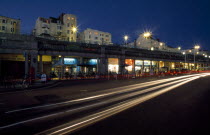 England, East Sussex, Brighton, Madeira Drive seafront promenade of shops and bars illuminated at night with traffic in motion blurr in the foreground.
