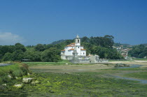 Traditional white church with bell tower and graveyard. Building alone in a field.