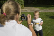 Mother taking a digital photograph of her son