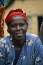 Burundi, Cibitoke District, Smiling woman sat with blue dress and red headscarf.