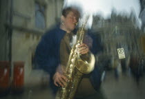 Travelling busker playing saxophone in Oxford.