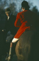 Riders on horseback with male rider wearing traditional red coat also known as hunting pink.