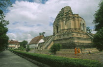 Wat Chedi Luang temple complex and ruined Lanna style chedi dating from 1441.  Monks walking past in the foreground.stupa