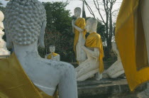 Wat Phra Mahathat.  Ruins of temple with seated and standing Buddha figures draped in yellow gold cloth.Unesco World Heritage site