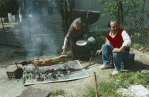 A couple roasting a lamb traditionally over coals outside at Easter.near Marathonnear Marathon