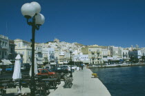 Ermoupolis. The town with benches and cafes at the waters edge with the orthodox church  Anastasi  on top of the hill bedind.