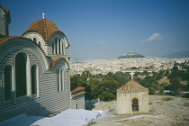 View of a church in the foreground and Acropolis and Lykavitos in the distance.