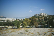 View of  Acropolis and Lykavitos behind a road with trees.