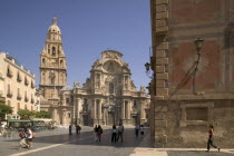 Cathedral de Santa Maria and Plaza del Cardenal Belluga with people walking past.  MediterraneanTravelTourismHolidays