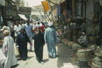 Busy souk market scene with pulse vendor and crowds walking by.