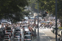 Harajuku. View looking up Omote-sando avenue to the intersection with Meiji-dori avenue with crowds on a pedestrian crossing  Saturday afternoon