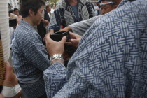 Traditional woden square cup for drinking sake  held by man in traditional Edo-era costume during Gion Matsuri FestivalFestival