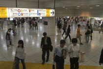 Tokyo station interior with crowds and bilingual color-coded signs above