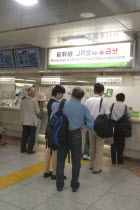 Tokyo station with customers waiting to buy Shinkansen aka bullet train tickets at a desk with bilingual signs above