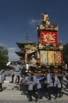 Members start to pull the neighborhood dashi or wagon in front of Narita san Temple during Gion Matsuri