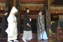 Nezu. Shinto priest leads newly married couple out of Nezu Jinja shrine after Shinto ceremony with bride and groom in traditional costume