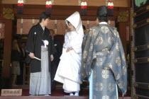 Nezu. Newlyweds after conclusion of Shinto ceremony at Nezu Jinja  both in traditional costume  while a Shinto priest waits for them