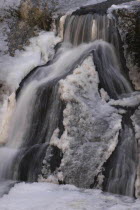 Fukuroda Waterfalls in the winter with the gushing water at the base of the falls partially frozen into ice